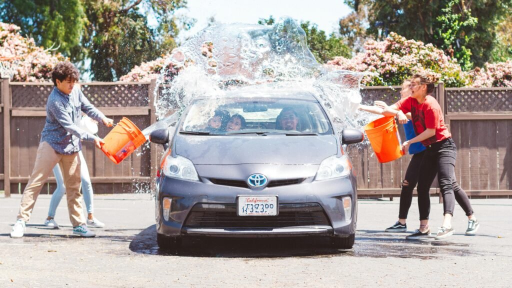 Group of people washing a car with buckets outdoors in Ventura, CA.